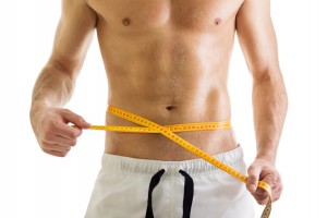 Fit body of shirtless man with tape measure
