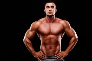 Handsome muscular man shirtless wearing white pants over black background